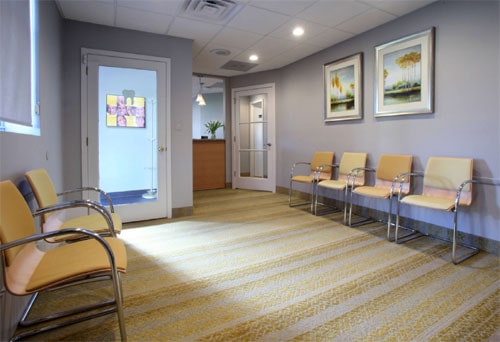 Modern waiting room with yellow chairs and framed art on the walls.