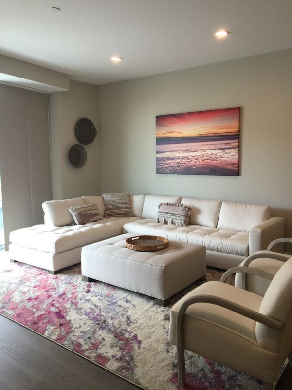 Cozy living room with neutral furniture, a colorful rug, and wall art decor.