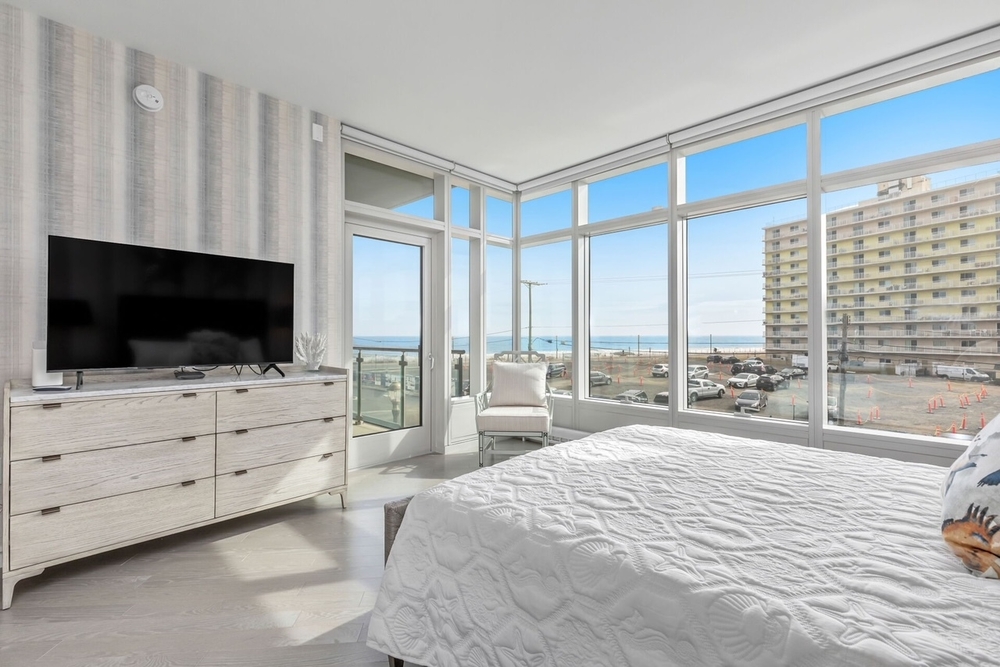 Bright bedroom with floor-to-ceiling windows showcasing natural light.